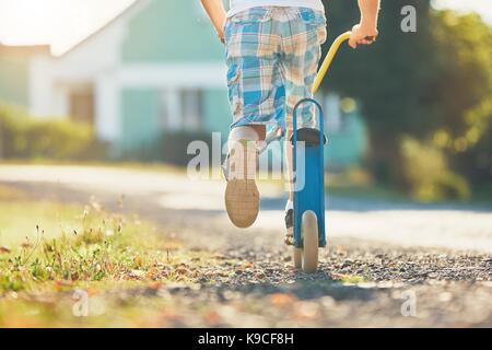 L'été à la campagne. little boy riding scooter push en journée ensoleillée. Banque D'Images