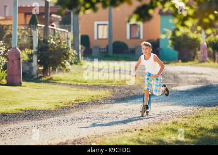 L'été à la campagne. little boy riding scooter push en journée ensoleillée. Banque D'Images