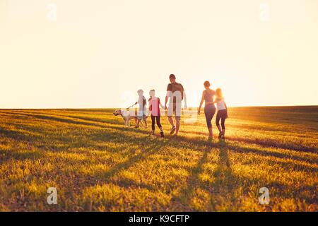 L'été à la campagne. silhouettes de la famille avec le chien sur le voyage au coucher du soleil. Banque D'Images