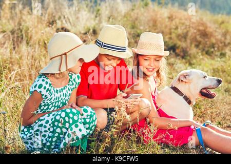 Heureux les enfants qui jouent avec smart phone. thèmes amitié, summertine et de la technologie moderne Banque D'Images