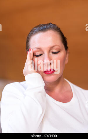 Portrait d'une femme d'âge moyen souffrant de maux de tête dans son appartement au dernier étage. Banque D'Images