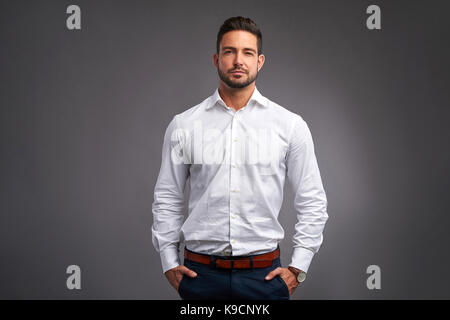 Un beau jeune homme confiant l'article au sérieux dans une chemise blanche. Banque D'Images