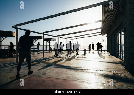 Silhouette de personnes marchant sur la terrasse au coucher du soleil Banque D'Images