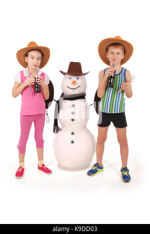 Cute boy and girl tenant une bouteille de cola à proximité d'un bonhomme de neige avec foulard et chapeau sur fond blanc Banque D'Images