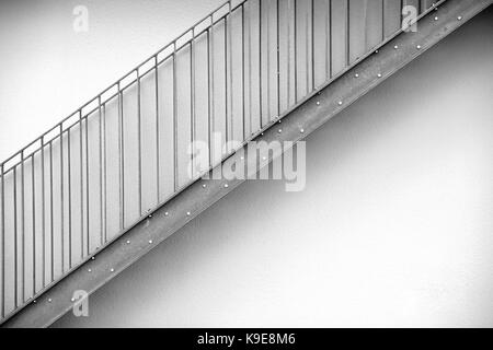 Détail d'un escalier extérieur moderne en face de clôtures disposées symétriquement. Banque D'Images