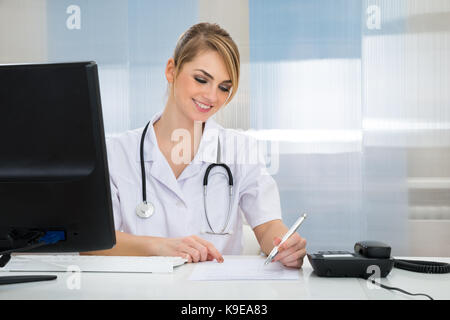 Portrait of happy young female doctor writing prescription Banque D'Images