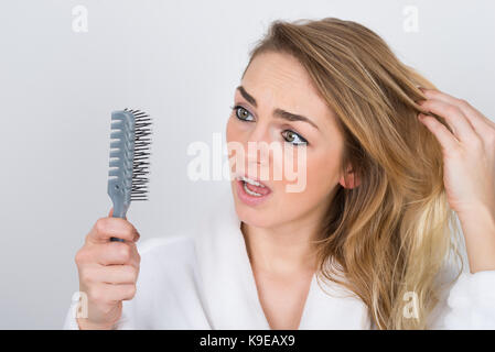 Peur femme souffrant de perte de cheveux à la recherche à comb Banque D'Images