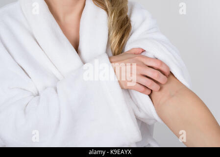 Close-up of a woman in bathrobe souffrant de démangeaisons Banque D'Images