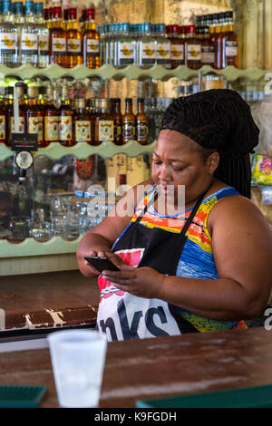 La Barbade. Bethsabée Beachside Bar servant des boissons et des rafraîchissements au rhum. Propriétaire de vérifier son téléphone cellulaire. Pour un usage éditorial uniquement. Banque D'Images