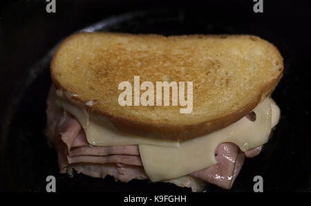 Un poêle en fonte et du pain au levain est une combinaison d'un grand sandwich. golden brown pain, jambon forêt noire et fromage suisse fondu. Banque D'Images