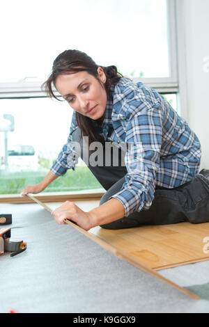 Smiling woman measuring wood flooring Banque D'Images