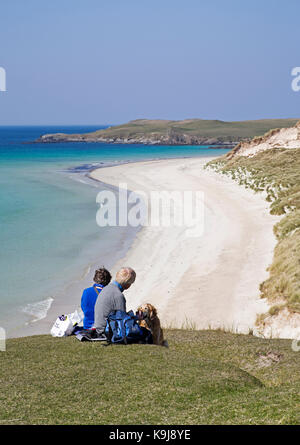 Deux femmes d'âge moyen avec dog having picnic sur le bord de la falaise surplombant la mer calme d'herbe et de sable blanc, la plage de Balnakeil Bay, Sutherland, UK Banque D'Images