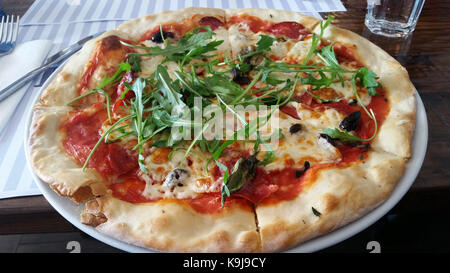 Tranches de pizza à la roquette et tomates cerises on white plate Banque D'Images