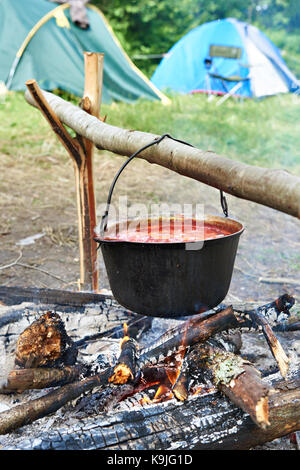 Bowler avec une soupe sur un feu de camp et d'tentes Banque D'Images