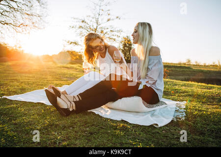 Belles femmes de boire du vin dans le parc sur une journée ensoleillée. Les amis et l'été. Banque D'Images