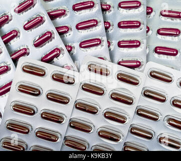 Tas de capsules rouges comprimés sous blister. Vitamines et suppléments concept Banque D'Images