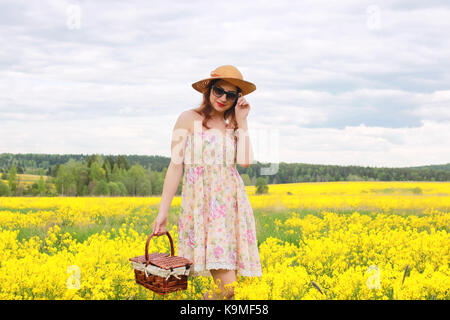 Jeune fille dans un champ de fleurs avec panier et un chapeau Banque D'Images