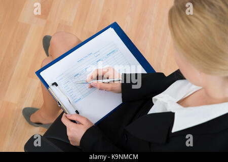 High angle view of businesswoman vide remplissage feuille de temps hebdomadaire in office Banque D'Images