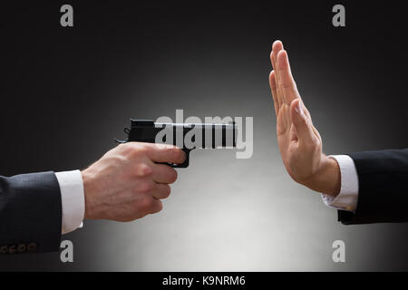 Close-up of woman with gun main pointant vers d'affaires gesturing stop Banque D'Images