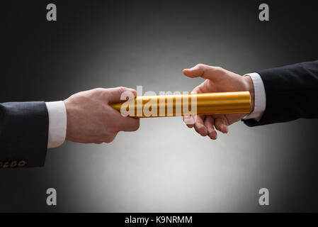 Close-up of businessman's hand passant un baton de relais d'or Banque D'Images