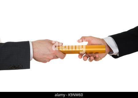 Close-up of businessman's hand passant un baton de relais d'or sur fond blanc Banque D'Images