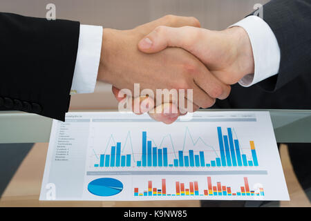 Close-up of businesspeople shaking hand in front of graph Banque D'Images