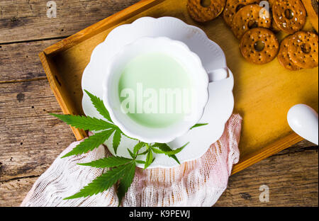 Lait vert avec de la marijuana dans une tasse sur la table en bois rustique Banque D'Images