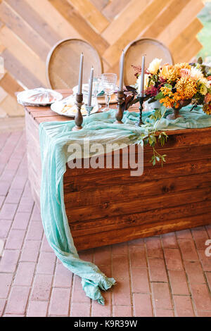 Réglage de la table, décoration de mariage concept. Il y a beaucoup de bougies dans des titulaires, merveilleux bouquet de fleurs et pour les clients de traitement préparés sur table en bois avec drapé turquoise Banque D'Images