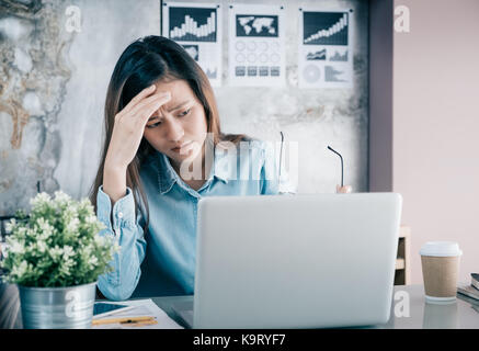 L'Asie a souligné creative designer femme couvrir son visage avec la main et se sentir contrarié de travailler en face de votre ordinateur lors de l'établissement social,l'office du stress Banque D'Images