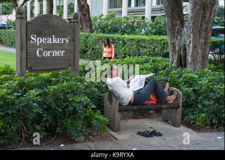 31.08.2017, Singapour, République de Singapour, en Asie - Un homme est assis sur un banc au coin des orateurs à Hong Lim Park et lit le journal. Banque D'Images