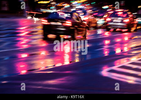 Trafic ville floue pittoresque avec des phares. Les voitures qui circulent sur la route de nuit après la pluie. Banque D'Images