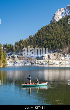 Deux pêcheurs dans une barque sur le lac en face de spitzingsee montagnes enneigées, des falaises et des forêts de montagne au printemps, Bavière, Allemagne Banque D'Images