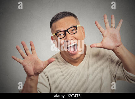 Super gros plan avec des lunettes guy funky excité en vous regardant mains armes soulevées au fond de mur gris isolé de l'appareil photo Banque D'Images