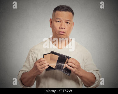 Closeup portrait souligné, contrariée, triste, malheureux homme d'âge moyen avec permanent, holding empty wallet gris fond Mur isolé difficile financière. Banque D'Images