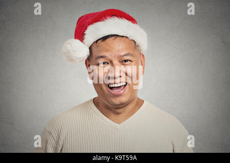 Closeup portrait portrait of man with red santa claus hat happy smiling, isolé sur fond de mur gris. visage positif expression, emoti Banque D'Images