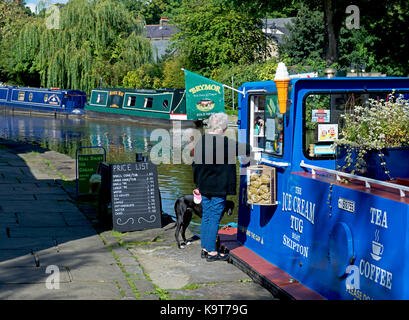 Femme l'achat de la crème glacée à partir du décrochage flottante, le Leeds et Liverpool Canal à Skipton, Yorkshire du Nord, Angleterre Royaume-uni Banque D'Images