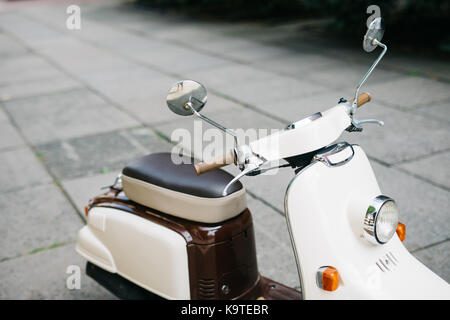 Scooter blanc est garée près de l'ancien mur de béton blanc,scooter est garé près de l'ancien mur en béton avec fond de ciel bleu, Banque D'Images