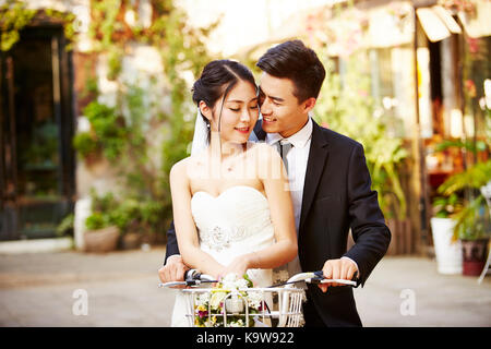 Heureux mariés asian couple having fun riding a bicycle. Banque D'Images