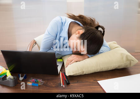 Young businesswoman sleeping at desk in office Banque D'Images
