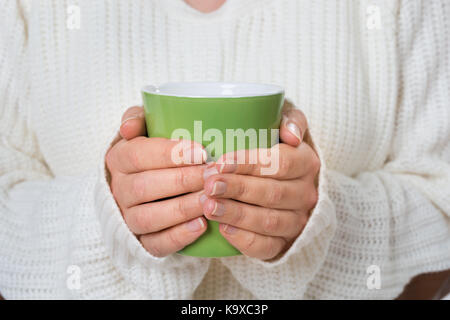 Close-up of personne hand holding mug vert de boisson chaude Banque D'Images