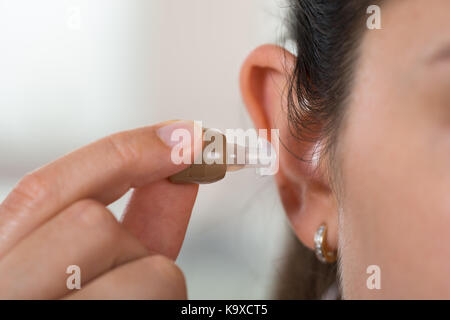 Close-up of female hand inserting aide auditive dans l'oreille Banque D'Images