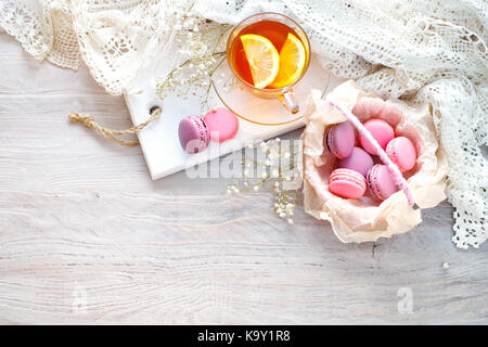 Thé au citron, fleurs sauvages et macaron sur table en bois blanc. La vie toujours délicate. Banque D'Images