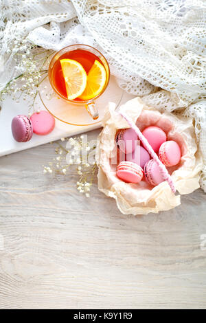 Thé au citron, fleurs sauvages et macaron sur table en bois blanc. La vie toujours délicate. Banque D'Images