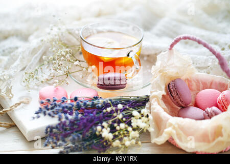 Thé au citron, fleurs sauvages et macaron sur table en bois blanc. La vie toujours délicate. Banque D'Images