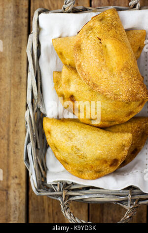 Empanadas fraîchement cuits au four avec légumes tartes chiffre d garniture de fromage en sauce tomate en panier d'osier. plank. bois d'Amérique latine espagnol tr Banque D'Images