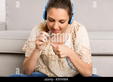 Belle femme à la maison faire une pause à la peinture ses ongles tout en écoutant de la musique Banque D'Images