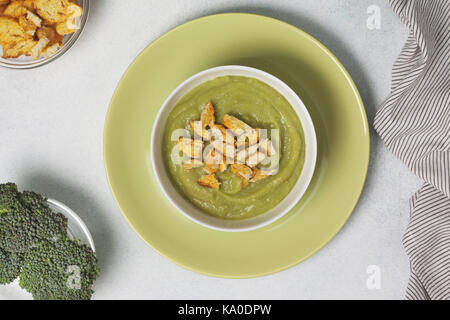 Purée de brocoli soupe avec des croûtons dans un bol blanc sur une plaque verte sur un fond blanc. Vue de dessus Banque D'Images