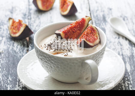 Yaourts aux figues, amandes et noix et miel dans une tasse blanche sur fond de bois vieux Banque D'Images