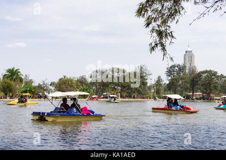 Les personnes bénéficiant de colporter des promenades en bateau ainsi que de s'asseoir près de Lake et à les regarder, Uhuru Park, Nairobi, Kenya, Afrique de l'Est Banque D'Images