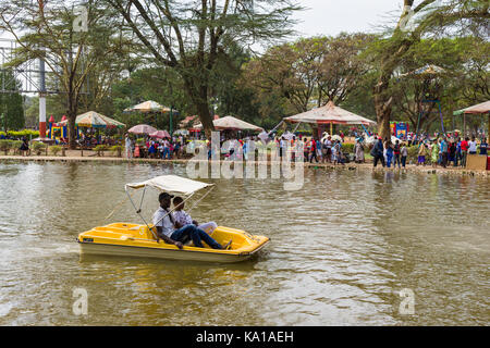 Les personnes bénéficiant de colporter des promenades en bateau sur le lac, de divertissement et des forains peut être vu en arrière-plan, Uhuru Park, Nairobi, Kenya, Afrique de l'Est Banque D'Images